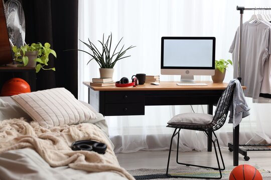 Teenager's room with stylish furniture, computer and houseplants. Interior design