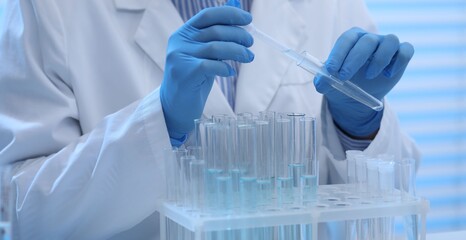Scientist dripping sample into test tubes in laboratory, closeup © New Africa