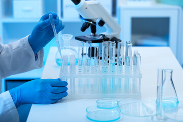 Fototapeta premium Scientist dripping sample into test tubes in laboratory, closeup