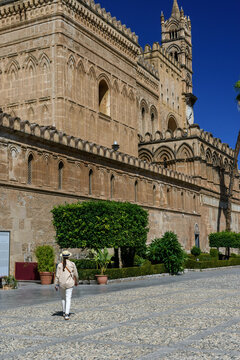 Turista caminando por la explanada adoquinada junto a la extensa fachada de la monumental catedral de Palermo en Sicilia, Italia..