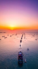 Obraz premium A serene aerial view of cargo ships navigating ocean waters at vibrant sunset, evoking a peaceful sense of global trade and logistics. Beautiful maritime scene with no people.