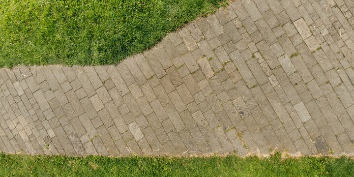 top view of the texture of paving slabs on pedestrian path with grass