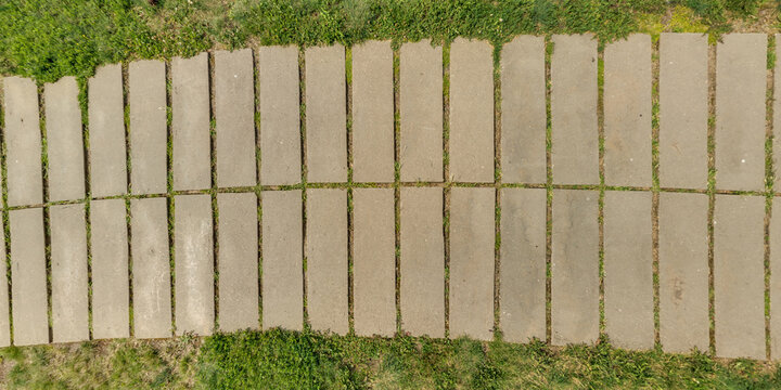 top view of the texture of paving slabs on pedestrian path with grass