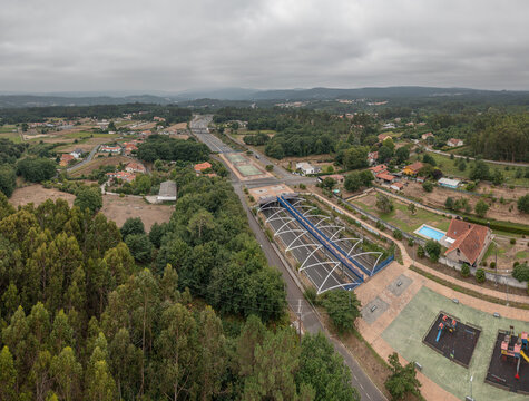 Aerial view of Parque Infantil De Oza and the nearby highway tunnel surrounded by lush greenery and rural landscape in Castres, A Coruna, Spain.