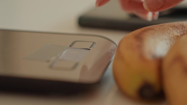 Kitchen weight demonstration. Digital scale with bananas. Closeup of kitchen scale measuring bananas for diet. Using digital kitchen scale to weigh bananas for portion control and meal tracking