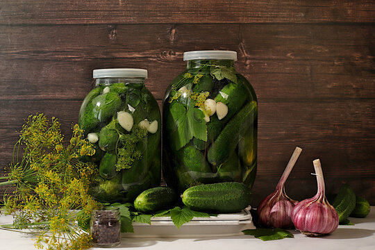 Pickled cucumbers in a jar with garlic and dill on the kitchen table, village harvest, homemade pickling recipe, cucumbers and ingredients for pickling, home canning concept, healthy and natural food.