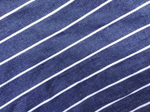 Blue denim fabric background with diagonal white pinstripe pattern