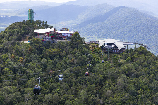 View of the Langkawi SkyCab cable car system with gondolas traversing over the dense tropical rainforest and mountain station in Langkawi, Kedah, Malaysia.