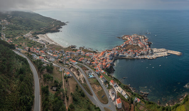 Aerial view of the coastal town of Caion with its harbor, sandy beach, and historic buildings situated on a peninsula in Caion, A Coruna, Spain.