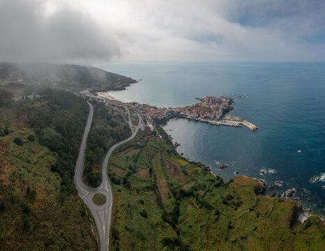 Aerial view of the coastal town of Caion with its harbor, winding roads, and green hills along the Atlantic coastline in Caion, A Coruna, Spain.