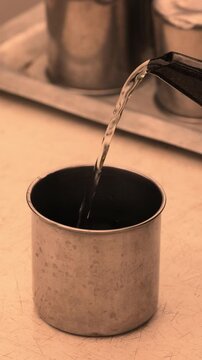 Water stream flowing into dark metal cup showing hydration concept