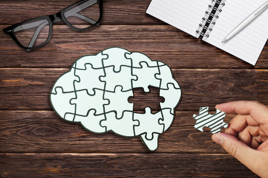 Mental health concept. Brain Puzzle with Missing Piece on Wooden Table. 
