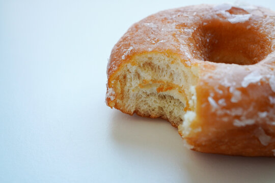 Glazed donut with a bite taken out on a white background