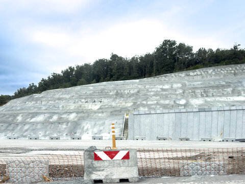 View of a large concrete retaining wall at a construction site with a steep hillside and trees in the background Sariyer, Istanbul, Turkiye.