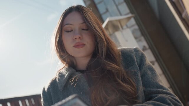 Pretty asian illustrator in quiet closeup, lowangle sunlit portrait with sketchbook, soft backlight on hair, calm eyes and gentle smile while reviewing page, intimate cinematic atmosphere