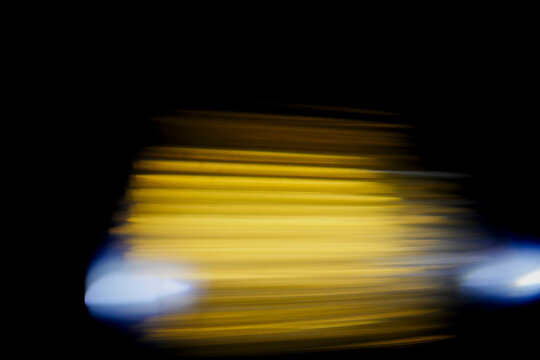 Abstract blur of warm yellow and cool blue lights against dark background. Perfect for creative design projects, tech themes, or nightlife concepts. Evokes mood of motion, energy, and urban vibrancy
