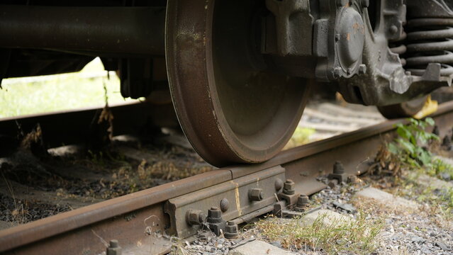 Close view of railway train wheel on steel track with rail fasteners and infrastructure components, transportation engineering detail