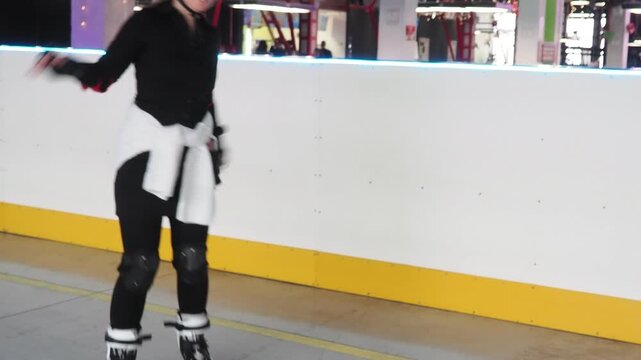 Girl roller skating having fun indoors. A girl learns to roller skate on a special area wearing a helmet and knee pads. Active sports for children