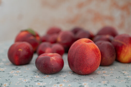 Fresh nectarines arranged on pale blue floral fabric