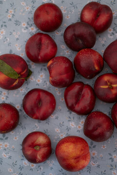 Ripe red nectarines arranged on blue floral fabric