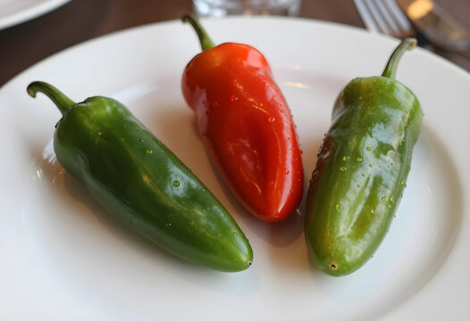 Fresh green and red chili peppers with water droplets on a white plate, spicy food and healthy eating