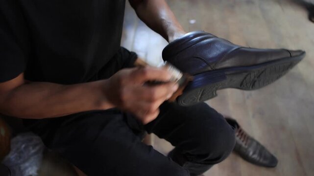 Close-up of male hands applying polish cream to a leather shoe. A professional shoeshiner polishing a shoe with cream and a brush.