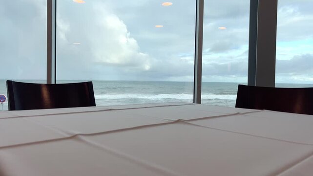 Table by seaside window in restaurant, calm ocean view interior