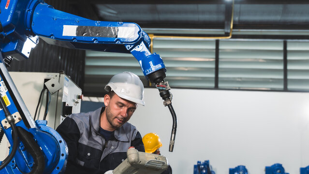 Professional technician monitoring robot operation During Robotic Equipment Maintenance in a Modern Manufacturing Plant