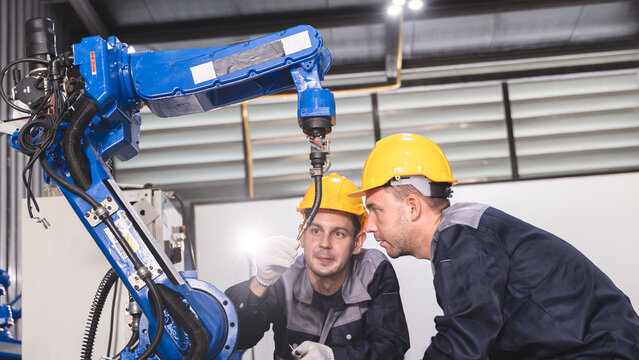 Industrial Workers reviewing machine controls While Evaluating Automated Machinery and Robotic Equipment During Close Range Fault Diagnosis