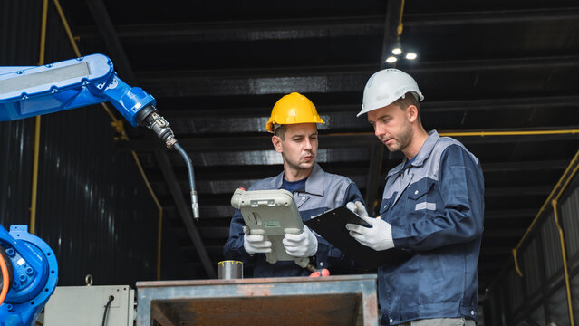 Industrial Automation Specialist reviewing machine controls Near a Blue Robotic Arm in a Production Environment Scene 319