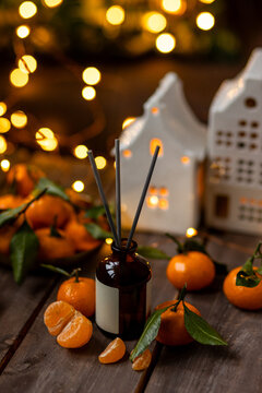 Scented aromatic candles on wooden table, liquid reed diffuser with sticks with citrus, cinnamon, anise, gingerbread cookies scent. Xmas spirit, creating holiday atmosphere, festive mood at home
