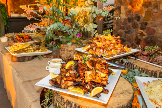 Peri peri chicken pieces on a white plate and various other foods on display at a function 