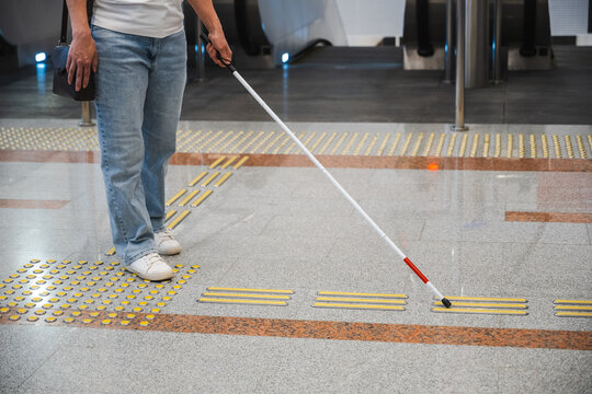 A blind woman in the metro near an escalator follows tactile navigation tiles.
