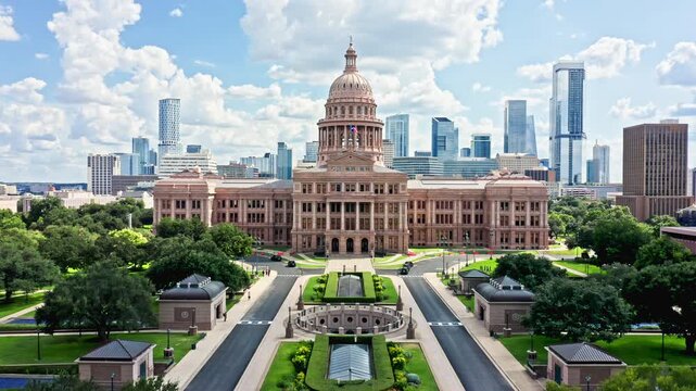 Slow camera lift in front of Texas State Capitol, the historic seat of government of Texas and one of the largest state capitol buildings in the United States, with Austin skyline in the background