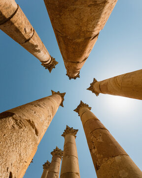 View of the ancient Roman columns with weathered stone and Corinthian capitals reaching towards a clear blue sky in Jerash, Jerash Governorate, Jordan.