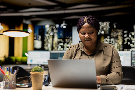 Black female analyst proofreads data reports after hours