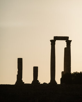 View of the ancient columns of the Amman Citadel silhouetted against a bright sky at sunset in Amman, Amman Governorate, Jordan.