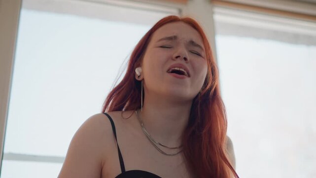 Vocal artist conveying deep feelings through dramatic illumination and scene. Expressive singer evokes powerful emotion while illuminated dramatically against luminous window backdrop