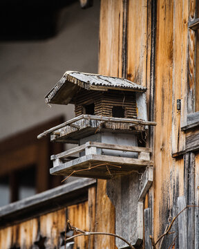 View of a rustic wooden birdhouse mounted on the weathered timber wall of a traditional house in Hallstatt, Upper Austria, Austria.