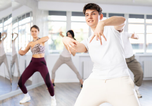 Guy conducts lesson for group of young people, demonstrates basic movements for performing locking dance, teaches modern dance culture directions