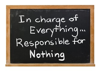 Fototapeta premium In charge of everything, responsible for nothing, written in white chalk on a black chalkboard isolated in a wooden frame on white