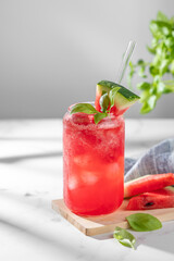 Naklejka premium A watermelon lemonade or mojito with ice and basil in a glass on a marble background