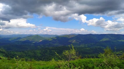 Fototapeta premium Panoramic View of Rolling Green Mountain Hills Under Cumulus Clouds