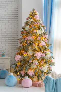 Festive Christmas tree decorated with pink and white flowers, silver ornaments and warm lights in bright cozy interior with pastel gifts. Festive aesthetic atmosphere, holiday mood