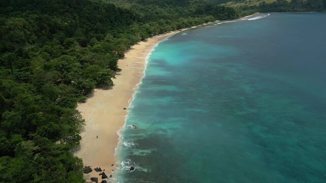Aerial view of Paal Beach with turquoise waters and lush tropical forest along the coastline in Likupang Timur, North Sulawesi, Indonesia.
