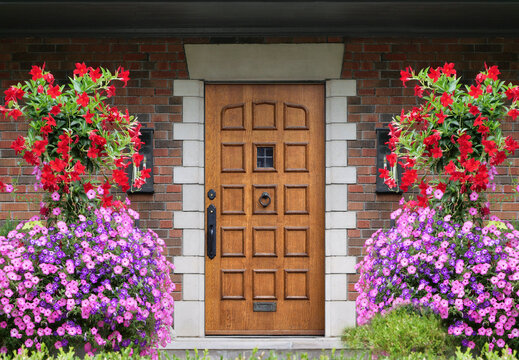 Elegant wooden front door of house surrounded by colorful flowers