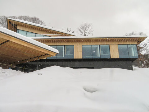 View of a modern wooden building with large glass windows surrounded by deep snow in Niseko, Hokkaido, Japan.