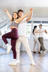 Naklejka premium Couple of young guy and young woman dancing latin dances in studio