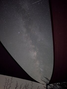 Voie lact&eacute;e clairement visible dans un ciel nocturne tr&egrave;s &eacute;toil&eacute;, photographi&eacute;e entre des toiles d'ombrage formant un cadre graphique autour du ciel.