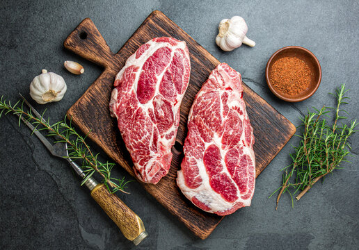 Raw pork cutlet chop for fry on pan with herbs, garlic on wooden boards, slate gray background